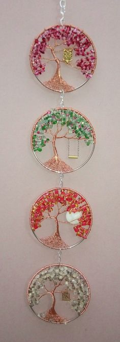 three tiered glass tree ornament hanging from a chain on a white wall