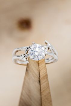 a diamond ring sitting on top of a wooden stand