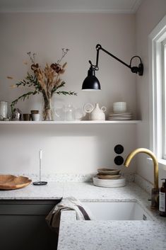 a kitchen with white counter tops and black accents on the shelves, along with flowers in vases