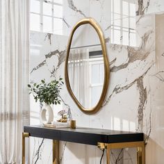 a console table with a mirror and vase on it in front of a marble wall