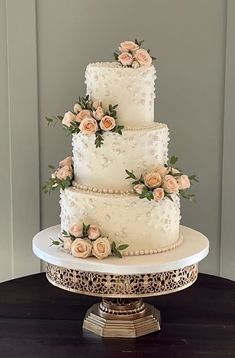 a three tiered wedding cake with pink flowers on the top and bottom, sitting on a table