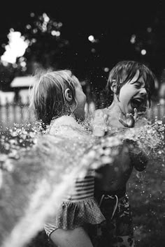 two children are playing in the water with their mouths open and one child is sticking his tongue out