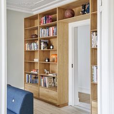 a living room filled with lots of wooden bookshelves next to a blue couch