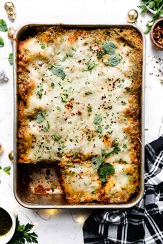 a casserole dish with cheese and herbs in it, being held by a spatula