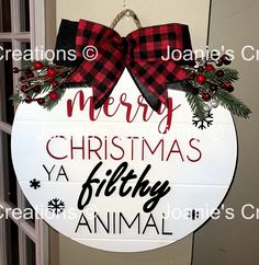 a merry christmas ya filthy animal sign hanging on the front door with red and black bows