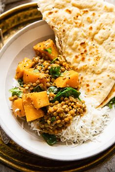 a white plate topped with rice and veggies next to a pita bread