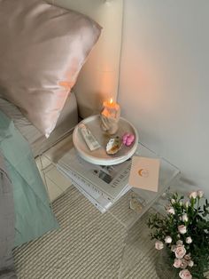 a table with some books and a candle on it next to a vase filled with flowers