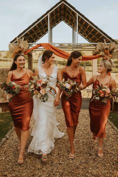 three bridesmaids walking down the aisle with their bouquets in hand and wearing orange dresses