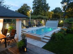 an outdoor hot tub in the middle of a decked area with chairs around it