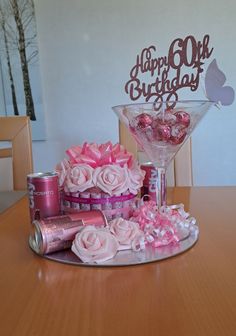 a happy 60th birthday cake with pink roses and candy in a martini glass on a table