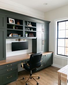 a home office with built in cabinets and desk