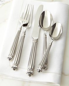 four silverware on a white napkin with two spoons and one fork