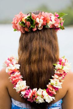 a woman with flowers in her hair wearing a blue dress and flower garland on her head