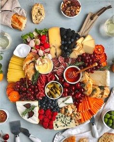 a platter filled with cheeses, fruits and other food on top of a table