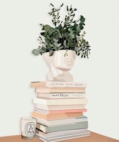 a stack of books sitting on top of a table next to a vase filled with plants