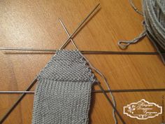 a pair of knitting needles next to a sock on a table with yarn in it