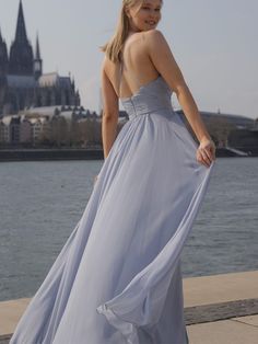 a woman in a long dress standing by the water