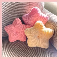 three crocheted stars sitting on top of a gray couch next to each other