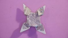 an origami star made out of money on a purple background with space for text