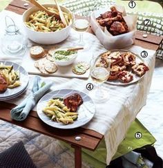 an outdoor table with plates of food and drinks on it, including meatballs and pasta