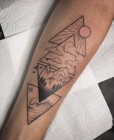 a person with a tattoo on their arm that has mountains and clouds in the sky