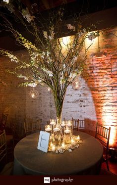 the table is set with candles and flowers in vases on it, along with an arrangement of branches