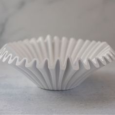 a white paper cup sitting on top of a marble counter next to a gray wall