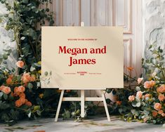 a sign that is standing in front of some flowers and greenery with the words megan and james written on it