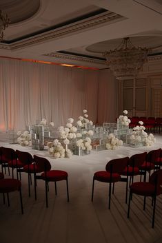 a room filled with lots of red chairs and tables covered in white flower centerpieces