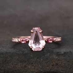 an engagement ring with a pink tourmaline stone and two diamonds on the side