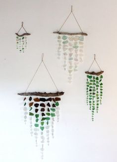 three wind chimes hanging on the wall with sea glass beads and pebbles in them