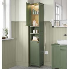 a green cabinet in the corner of a bathroom