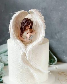 an angel figurine sitting on top of a white cake covered in icing