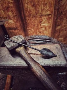 a pair of tongs sitting on top of a piece of wood next to a hammer