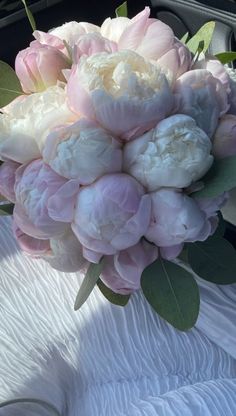 a bouquet of pink and white peonies in the back of a car