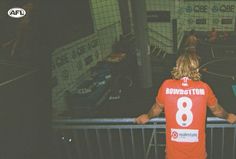 a man in an orange shirt is looking over a fence