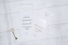 two white tags with gold foil on them next to a key