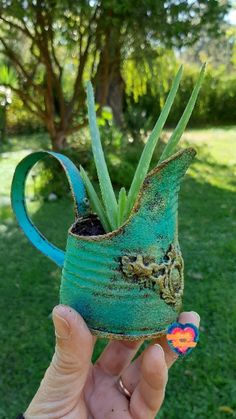 a person holding up a green vase with plants in it's mouth and an air plant growing out of the top