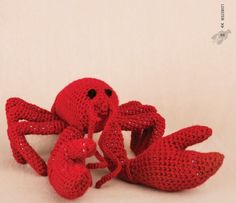 a red crocheted crab sitting on top of a white table next to two smaller crabs