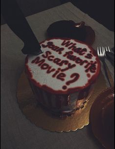 a cake with writing on it sitting on top of a table next to a knife and fork