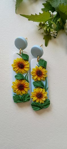 two sunflowers are sitting next to each other on a white surface with green leaves