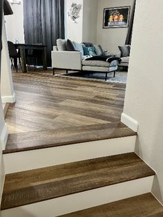 a living room filled with furniture next to a wooden flooring stair case on top of a hard wood floor