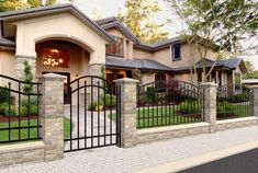 a house with an iron fence in front of it and trees around the entrance area