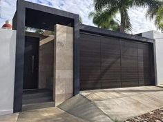 the entrance to a modern home with large garage doors and palm trees in the background