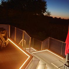 a woman standing on top of a wooden deck next to a red umbrella at night