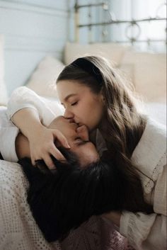 a woman laying on top of a bed next to a young man with long hair