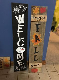 two wooden welcome signs sitting next to each other on top of a tile floor in front of a blue wall