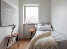 a bedroom with white walls and wood flooring has a large painting on the wall