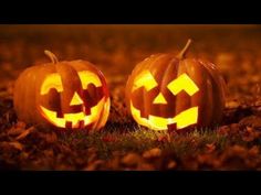 two carved pumpkins sitting in the grass