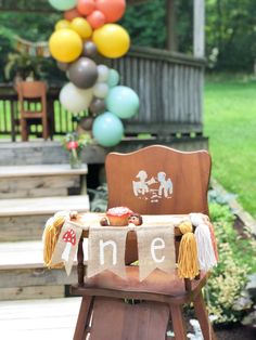 a wooden chair sitting in front of some balloons